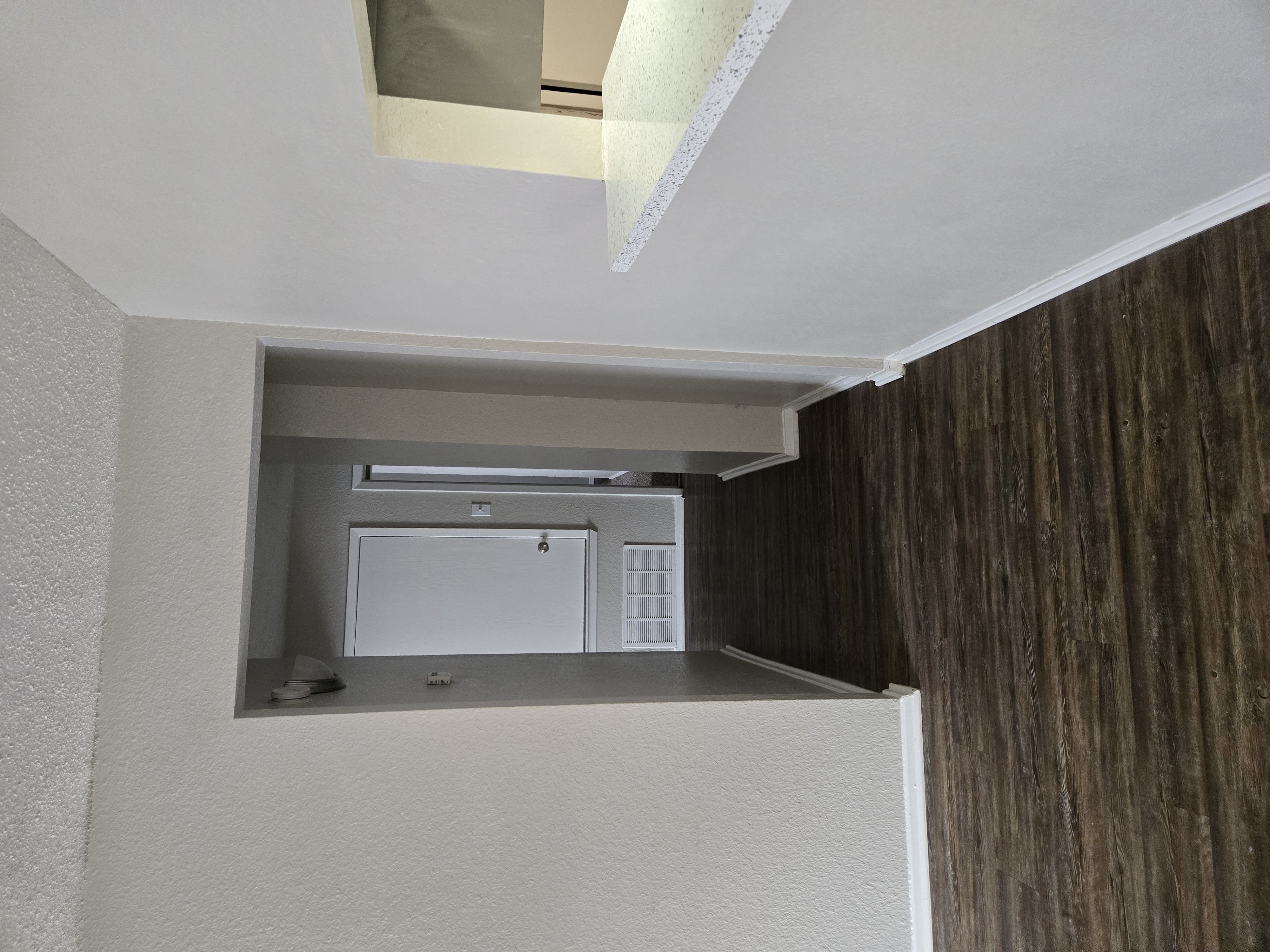 A white appliance is installed in a corner of a room with a wooden wall.